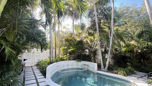 A swimming pool with a tiled deck and surrounding tropical vegetation. - Casa Marina Cottage+ private pool+walk to Duvall st. (Key West)