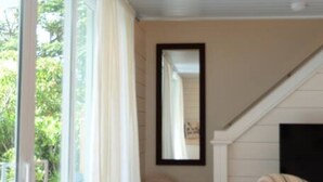 A modern interior with a large sliding glass door leading to a balcony, a mirror on the wall, and a sofa in the corner. - Casa Marina Cottage+ private pool+walk to Duvall st. (Key West)