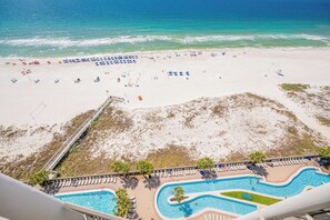 A beach resort with a swimming pool, beach umbrellas, and lounge chairs. - Beachfront Luxury at The Oasis 1405 | Sleeps 11 (Orange Beach)