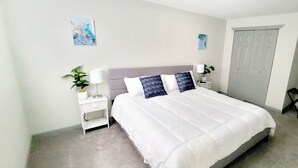 Ein Schlafzimmer mit einem Bett, Nachttischen, einem Schrank und einem Sessel, außerdem ein Blumentopf.
