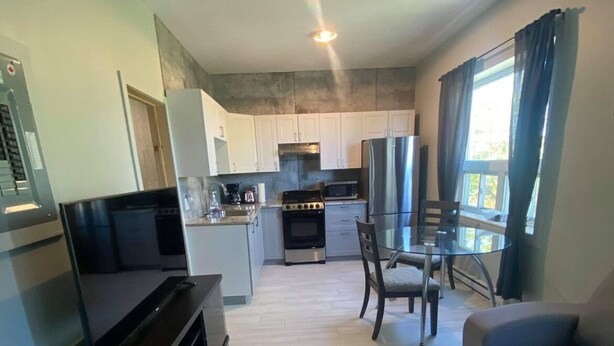 A compact living space with a kitchenette, a dining area, and a seating area. - Le Convivial (Rouyn-Noranda)