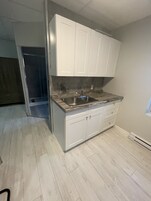 Uma cozinha com armários brancos, uma pia de aço inoxidável e bancada de madeira.