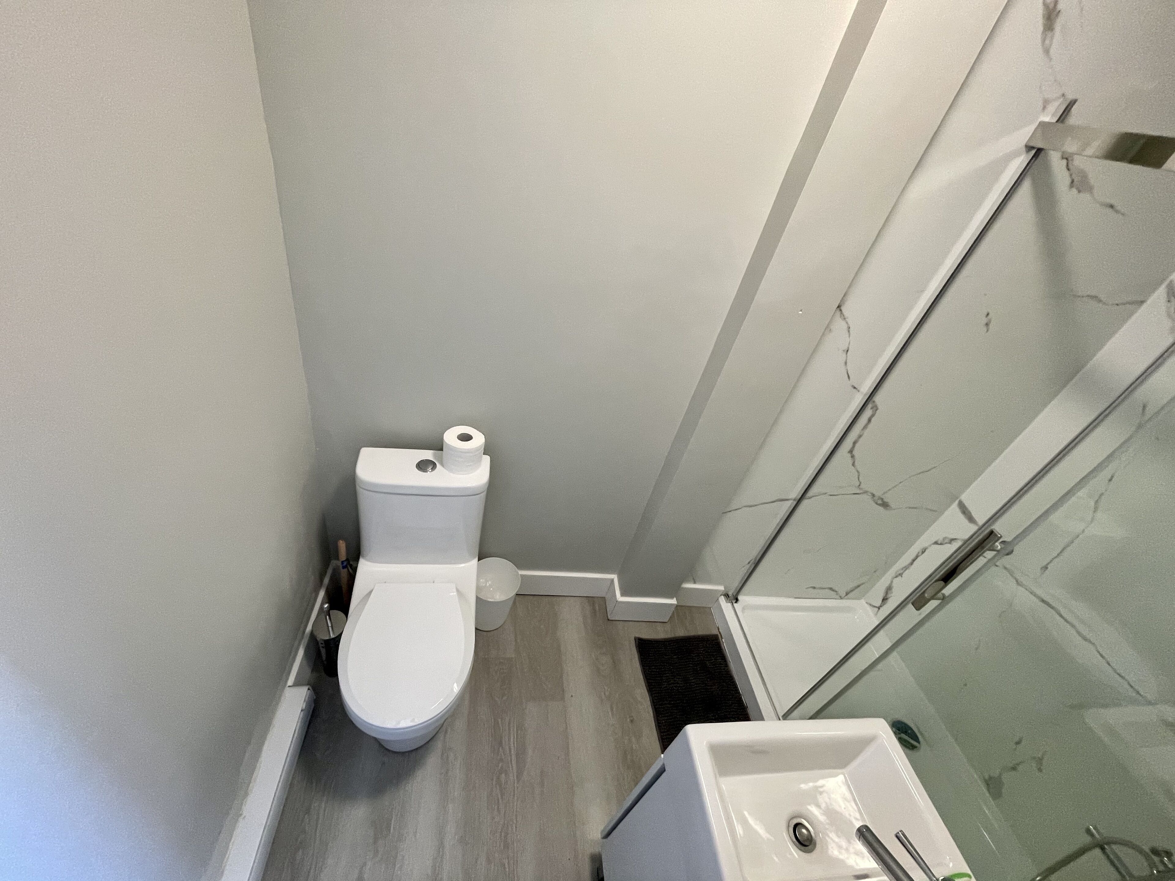 Une salle de bain équipée de toilettes, d’un lavabo et d’une douche à parois de verre.
