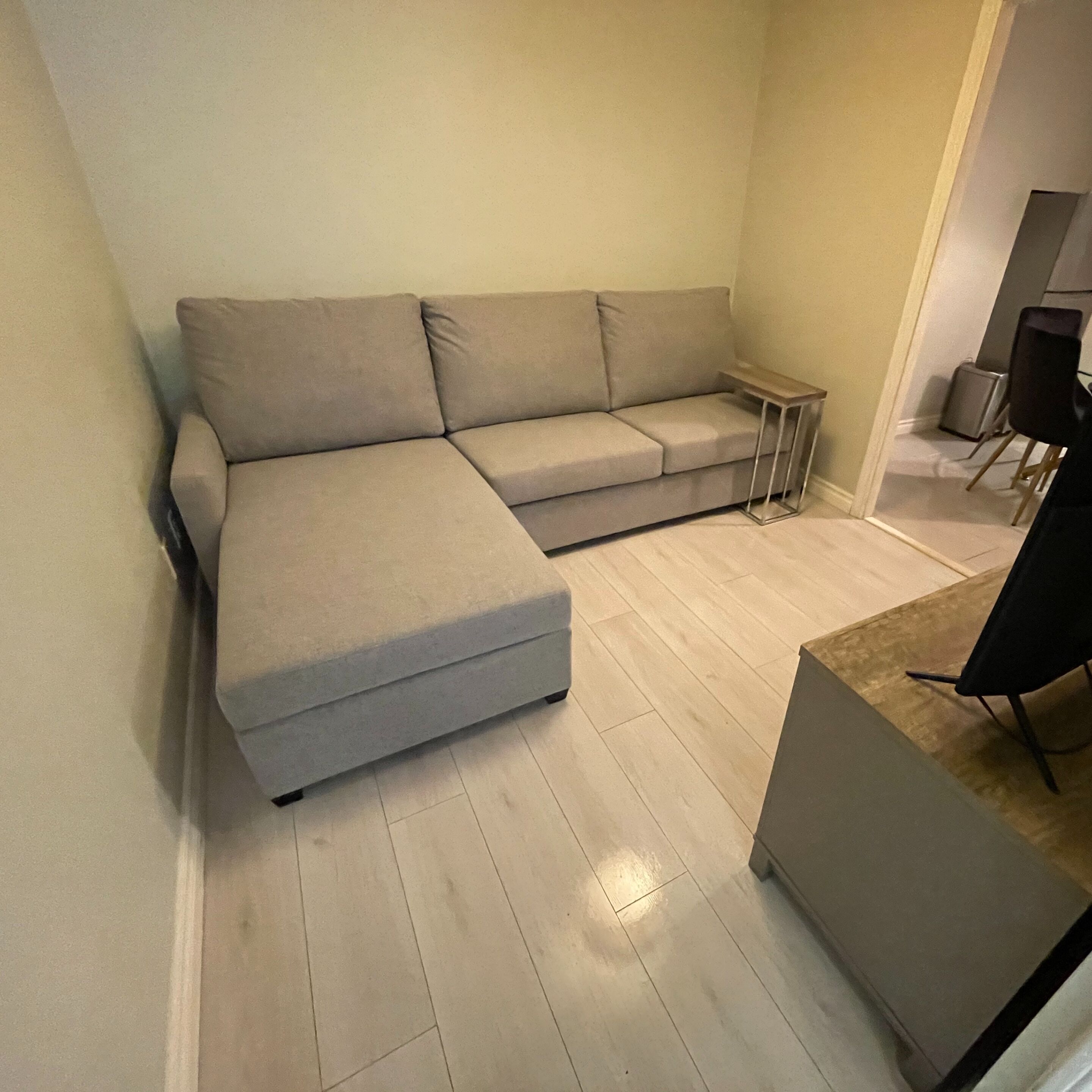 Una sala de estar moderna con un sofá seccional gris, una mesita auxiliar y suelo de madera.