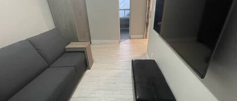 Una sala de estar con un sofá, un banco, un televisor y un aparador de madera.