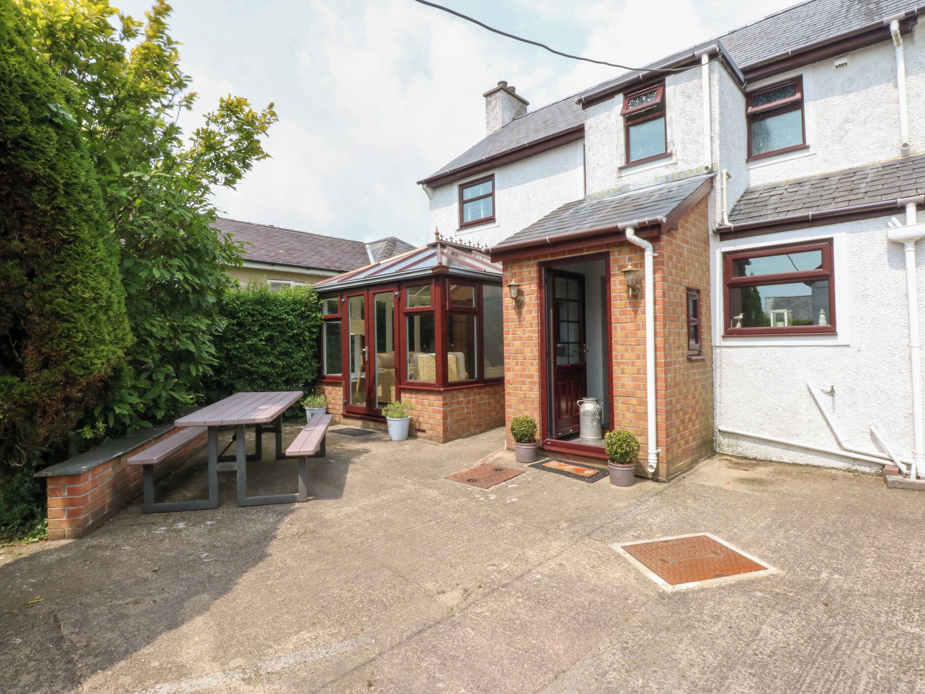 A residential property with a patio area, a conservatory, and a brick exterior.