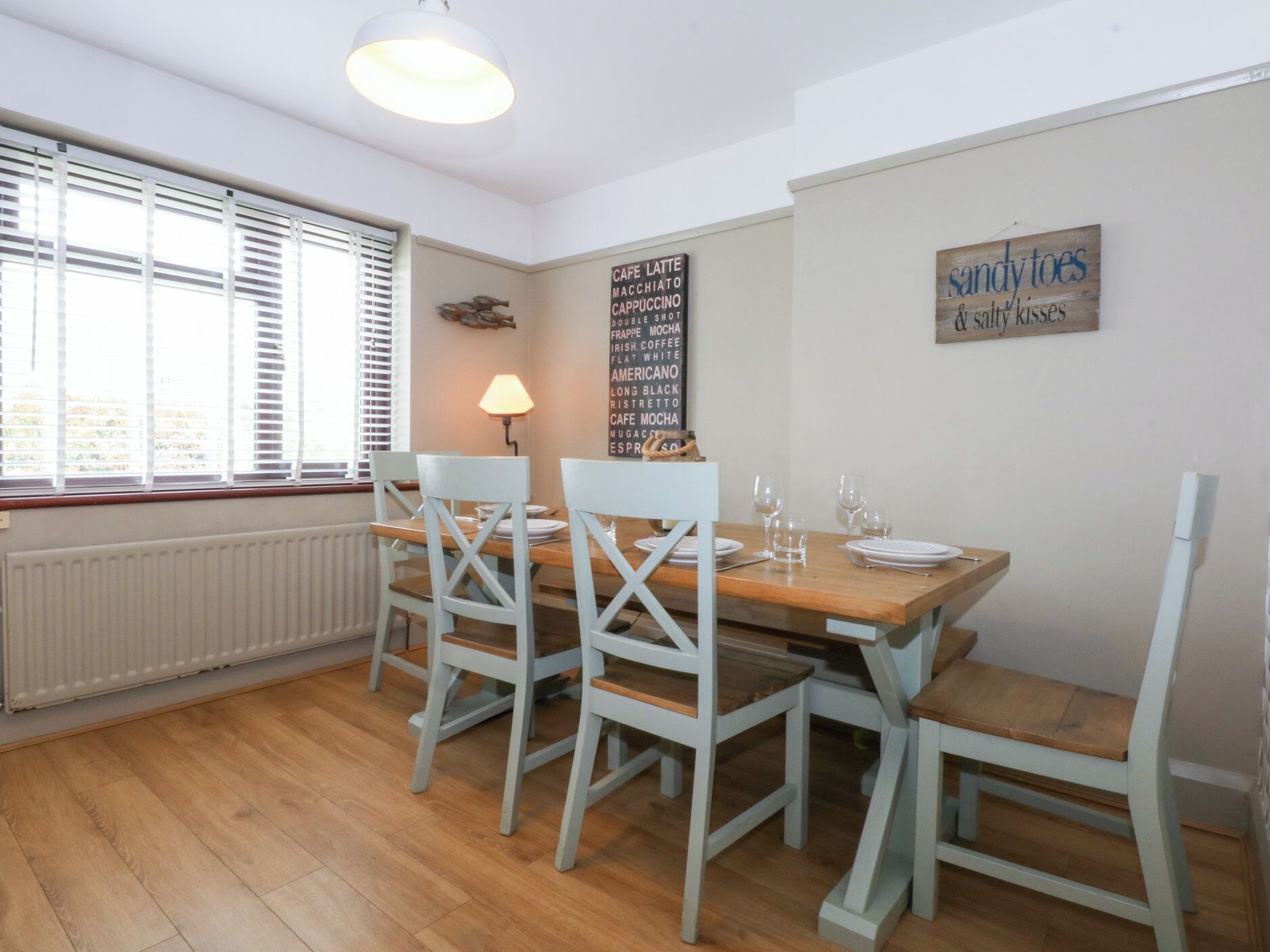 Een eetruimte met een houten tafel, vier stoelen en een menukaart aan de muur.