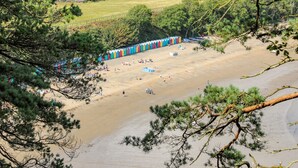 Une plage avec des cabanes de plage aux couleurs vives et un rivage sablonneux.