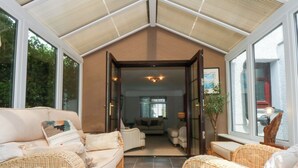 Un salon chaleureux, avec des meubles en osier, une grande fenêtre et une vue sur l’extérieur.
