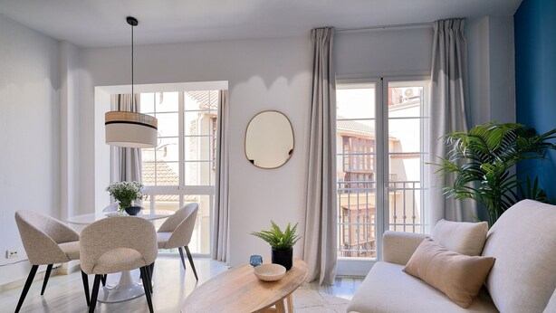 Una sala moderna con sofá, sillones, una mesa de centro de madera y una lámpara colgante.