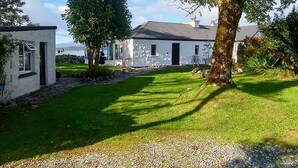 A white building with a gravel path leading to a grassy area.