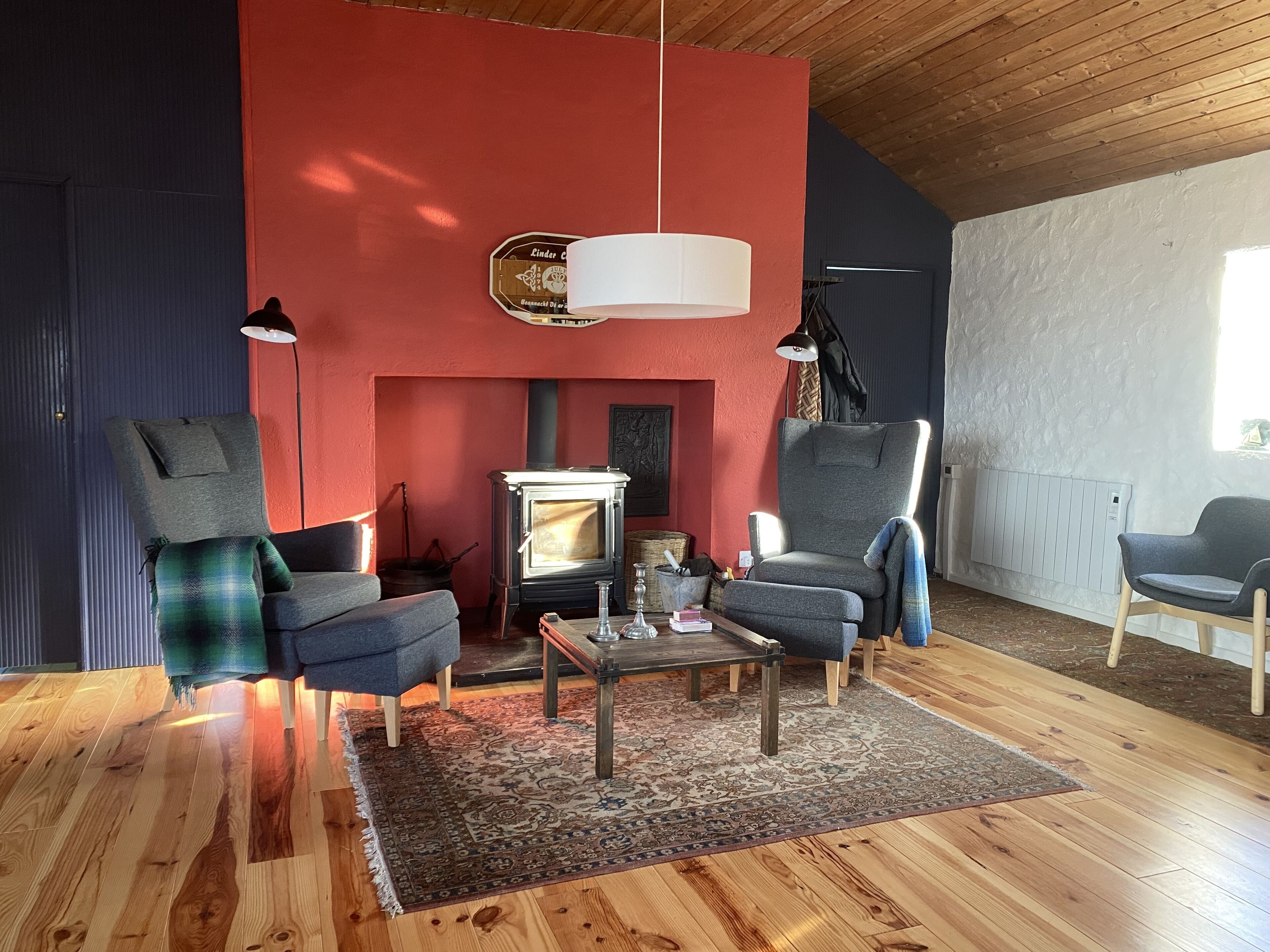 A cozy living room with a fireplace, two armchairs, a coffee table, and a hanging light fixture.
