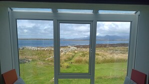 A room with a large window overlooking a grassy area and a body of water.