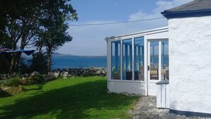 A white house with a glass conservatory overlooking a body of water.