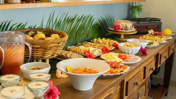 Ein reichhaltiges Buffet mit verschiedenen Speisen, darunter Früchte, Salate und Desserts, präsentiert auf einem Holztisch im tropischen Stil.