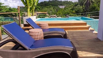 Relax by the pool with comfortable lounge chairs and lush green surroundings.