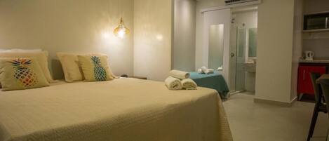 Habitación de hotel con una cama grande, un escritorio, una silla y un baño visible a través de una puerta abierta.