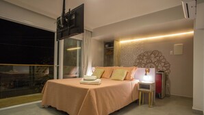 Ein Schlafzimmer mit einem großen Bett, einem an der Wand montierten Fernseher, einem Nachttisch und einem Beistelltisch.