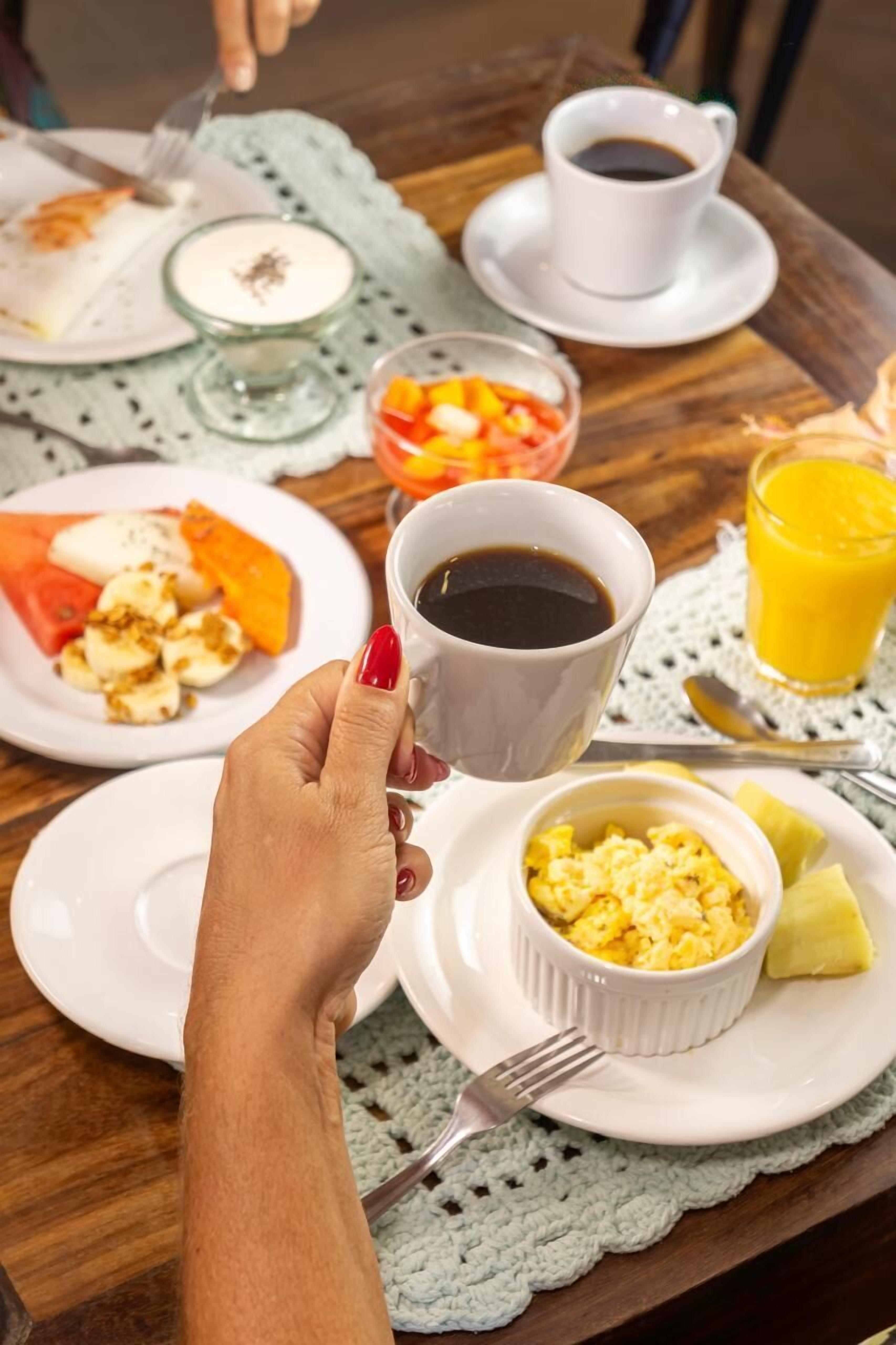 Een ontbijttafel met borden eten, een kop koffie en een glas sinaasappelsap.