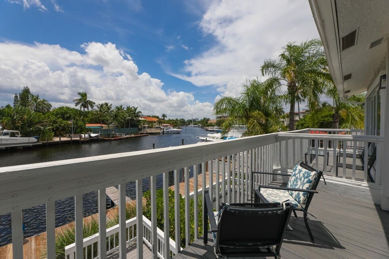 A balcony with a view of a marina, palm trees, and a clear sky.