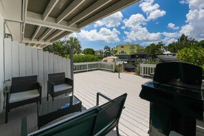 Eine Terrasse im Freien mit Grill, Sitzgelegenheit und Blick auf ein Gebäude im Hintergrund.