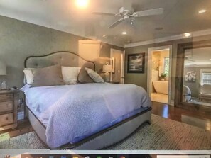 Relax in this serene bedroom with a large bed, nightstand, and ceiling fan.