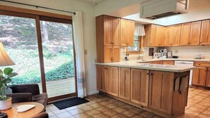 Eine Küche mit Holzausstattung, Spüle und Arbeitsplatte. Es gibt einen Essbereich mit Tisch und Stühlen.