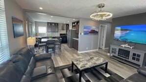 A modern living room with a leather sofa, a coffee table, and a flat-screen TV. - Elephant Lake Resort Oasis New (Elephant Butte)