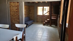 A room with a brick wall, a sofa, a staircase, and a TV. - Cabin Arroyo de Uco - Between mountains, streams and wineries (Manzano Historico)