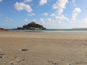 Una playa con un castillo en una pequeña isla al fondo.