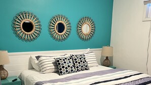 Une chambre à coucher comprenant un lit, deux tables de chevet et trois miroirs muraux.