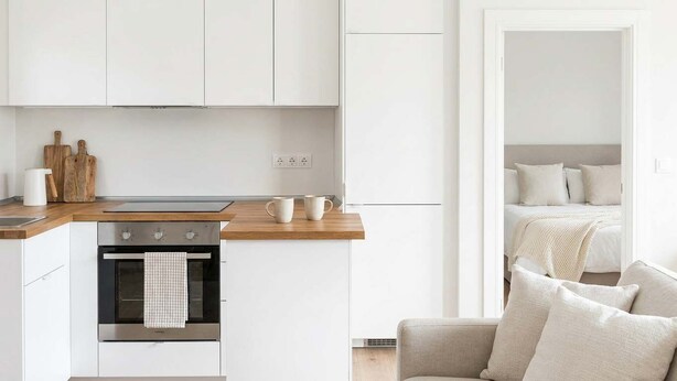 Eine moderne Küche mit weißen Schränken, einem eingebauten Backofen und einer Holzarbeitsplatte.