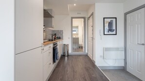 A modern kitchen with white cabinets, a wooden countertop, and a visible trash bin. - Bright 1BR Apt in Hunslet, Near Leeds Centre (Leeds)