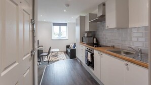 A modern kitchen with white cabinets, a wooden countertop, a built-in oven, and a stainless steel sink. - Bright 1BR Apt in Hunslet, Near Leeds Centre (Leeds)