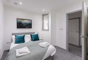 Experience a serene retreat with a large bed, two nightstands, and a functional workspace.