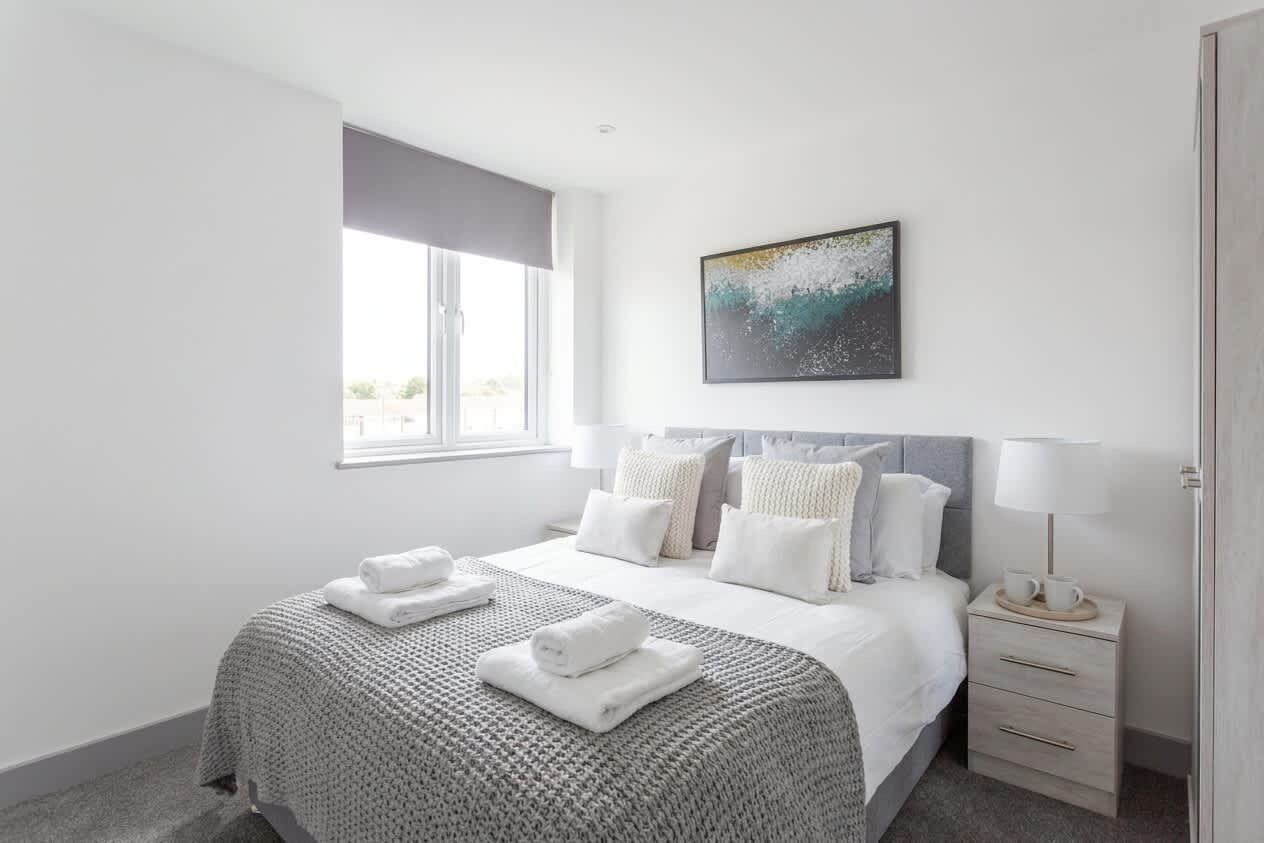 Een slaapkamer met een bed, nachtkastje en een raam.