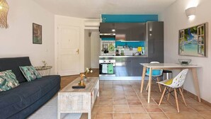 A living room with a sofa, a coffee table, and a dining area with a table and chairs. - Blue Bay Apartment, Orient Bay, near the beach (Collectivité de Saint-Martin)