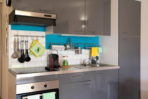 A modern kitchen with stainless steel appliances, a blue backsplash, and a variety of utensils and cookware.