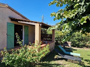 A house with a patio, a green door, and a garden with flowers and a lawn chair. - Studio for 2 persons (poggio mezzana)