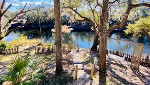 A pathway leading to a body of water surrounded by trees and a wooden fence.