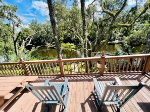A wooden deck with two blue chairs and a railing overlooking a pond surrounded by trees. - Peaceful cabin on the Cochee river w/ 4 acres land (Jasper)