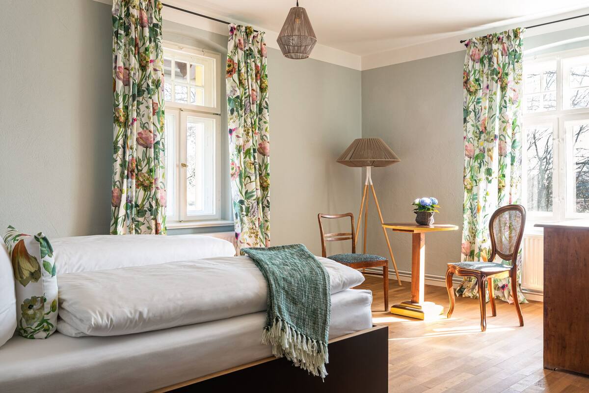 A bedroom with a bed, a chair, a lamp, and curtains.