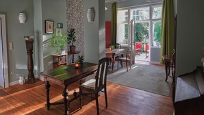 A dining area with a wooden table and chairs, a potted plant, and a view of the outdoors through a large window. - Klostergartenhotel Marienfliess (Marienfließ)