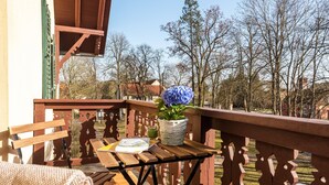 A wooden balcony with a table, a chair, and a potted plant. - Klostergartenhotel Marienfliess (Marienfließ)