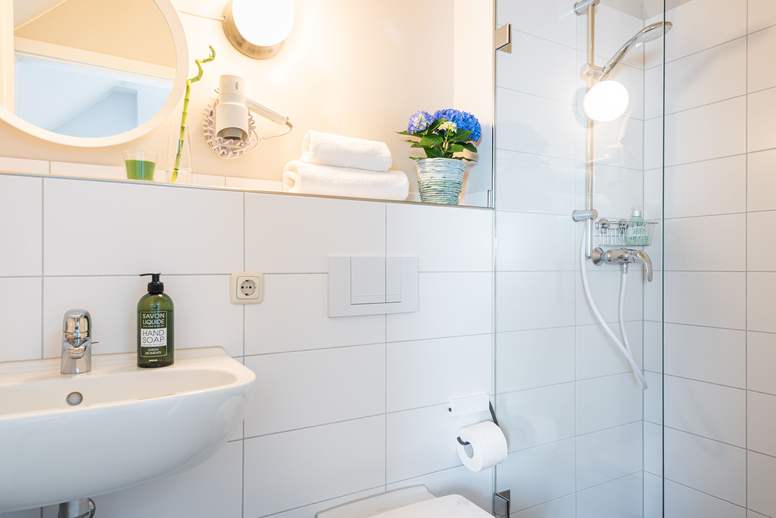 A modern bathroom with a sink, mirror, and shower.