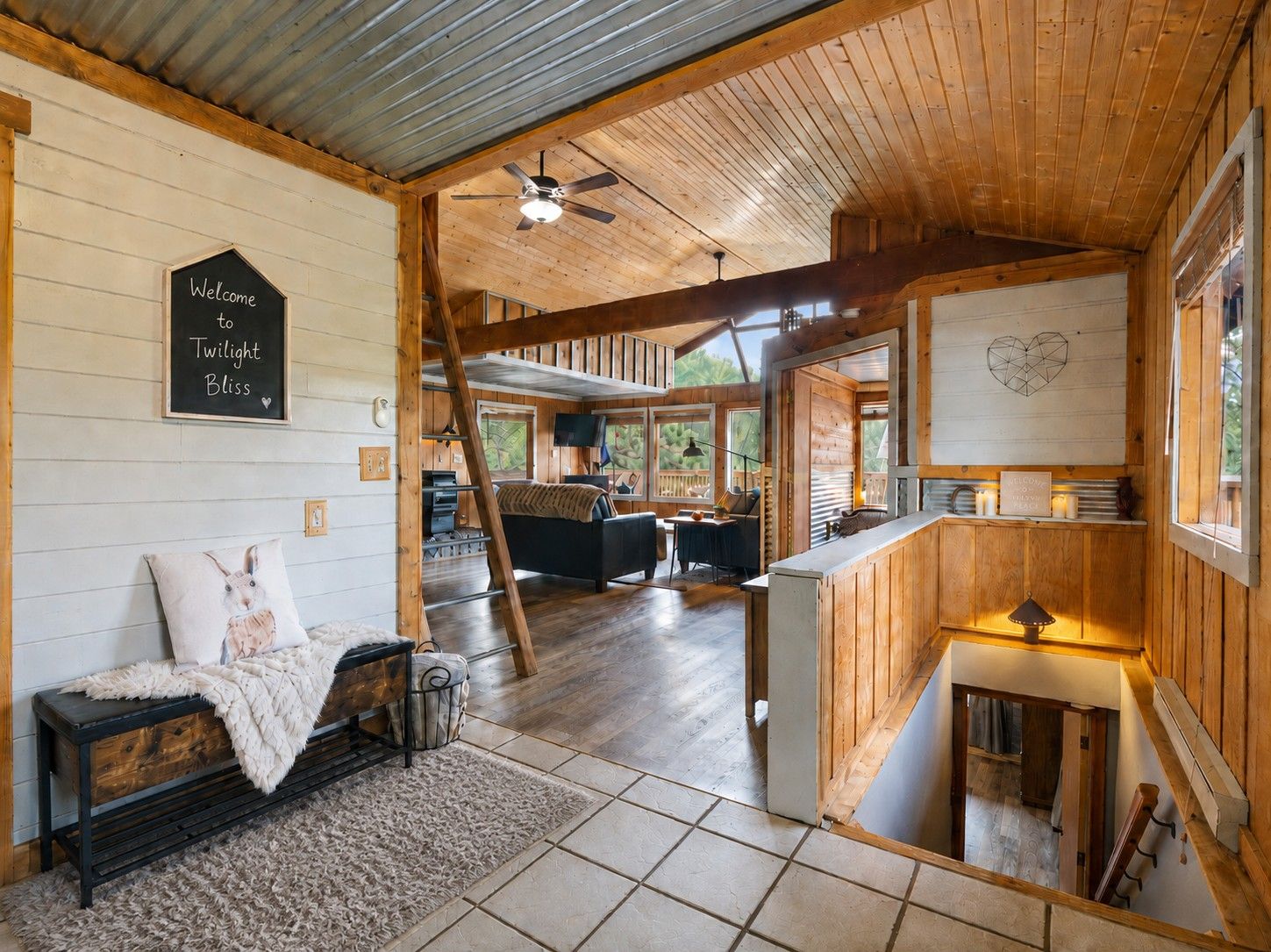 A cabin interior with a wooden ceiling, a fireplace, a sofa, and a dining area.