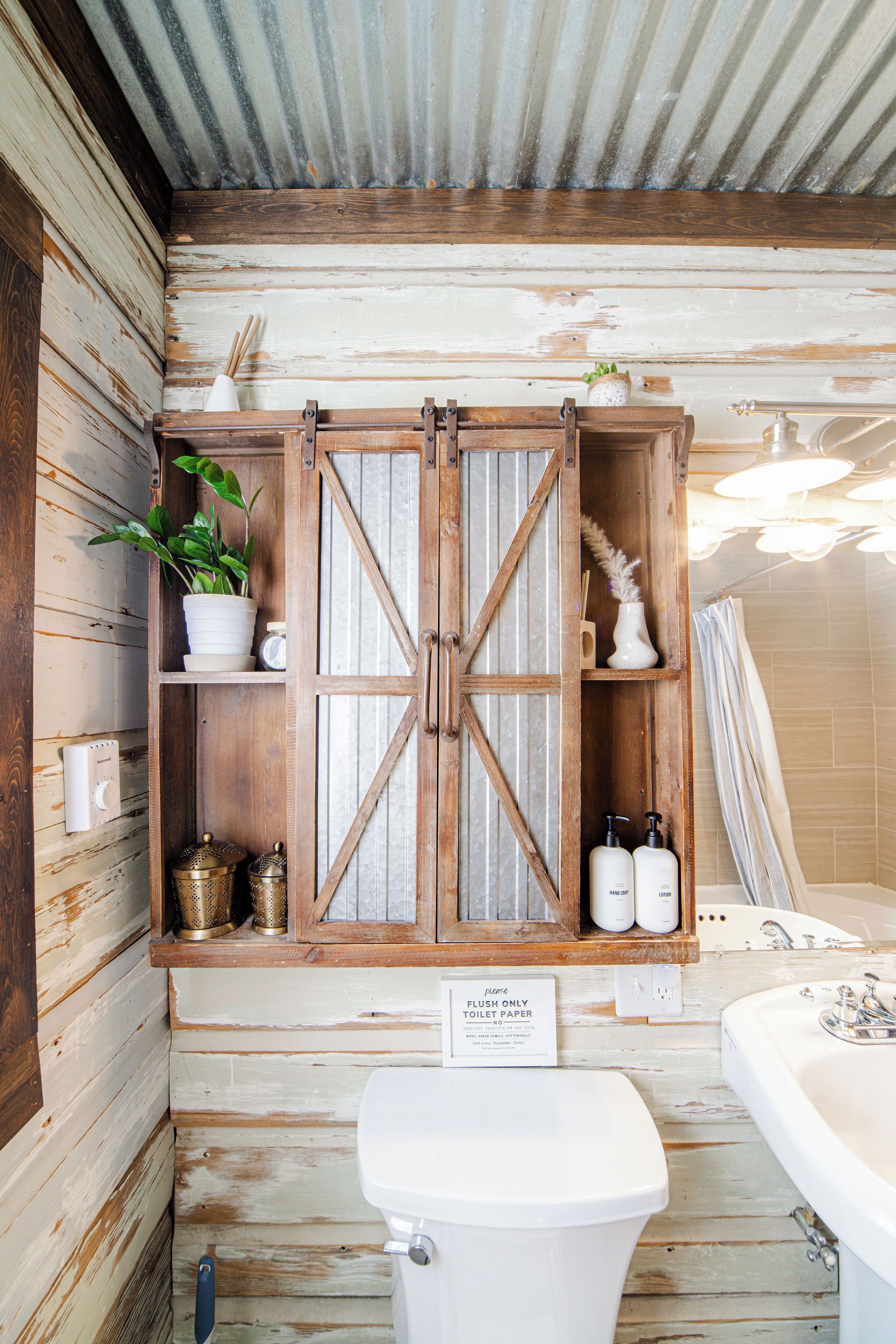 Une salle de bain rustique avec un meuble en bois, des toilettes et une baignoire.