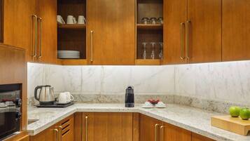 Una cocina con armarios de madera, encimera de mármol, cafetera y hervidor.
