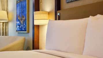 Una habitación de hotel con una cama bien hecha, un cuadro en la pared y una lámpara.