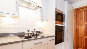 Uma cozinha moderna com armários brancos, forno embutido e bancada com panelas.